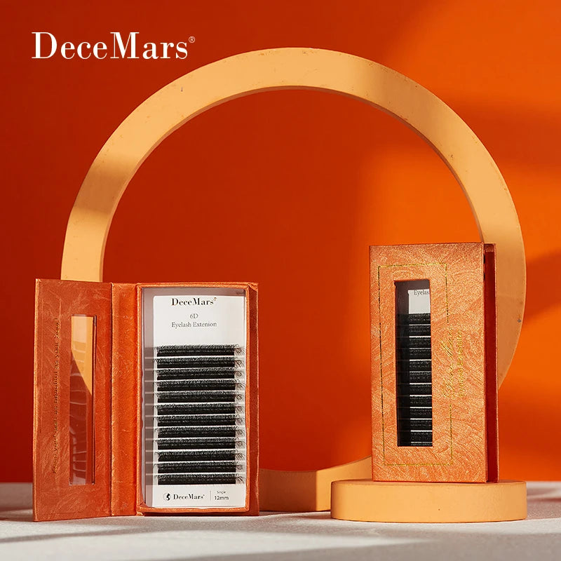 DeceMars 6D W-shaped black synthetic eyelash extensions in orange textured boxes displayed on orange podiums.