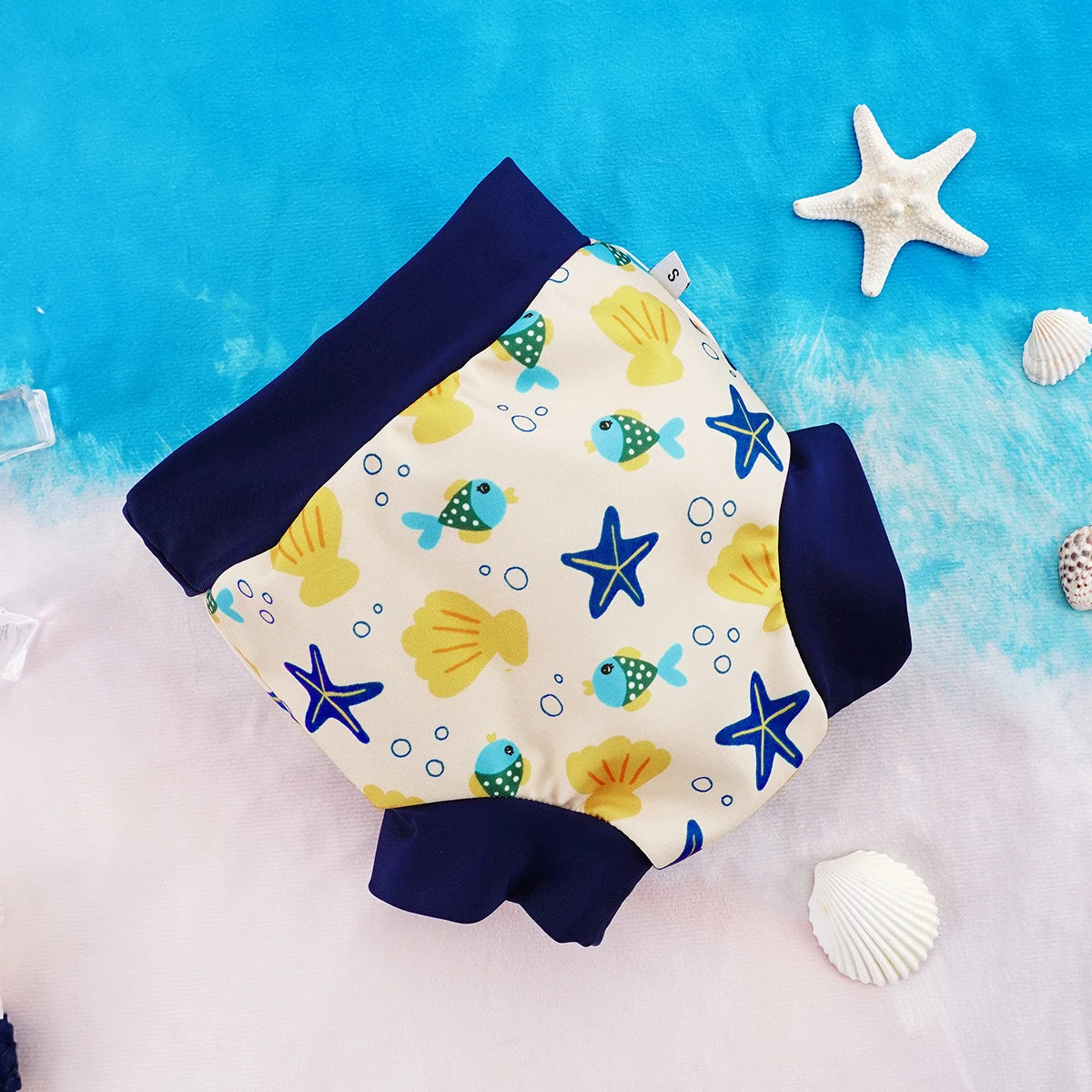 Small size baby swim diaper with ocean-themed fish, starfish, and seashell print on a blue and white background.
