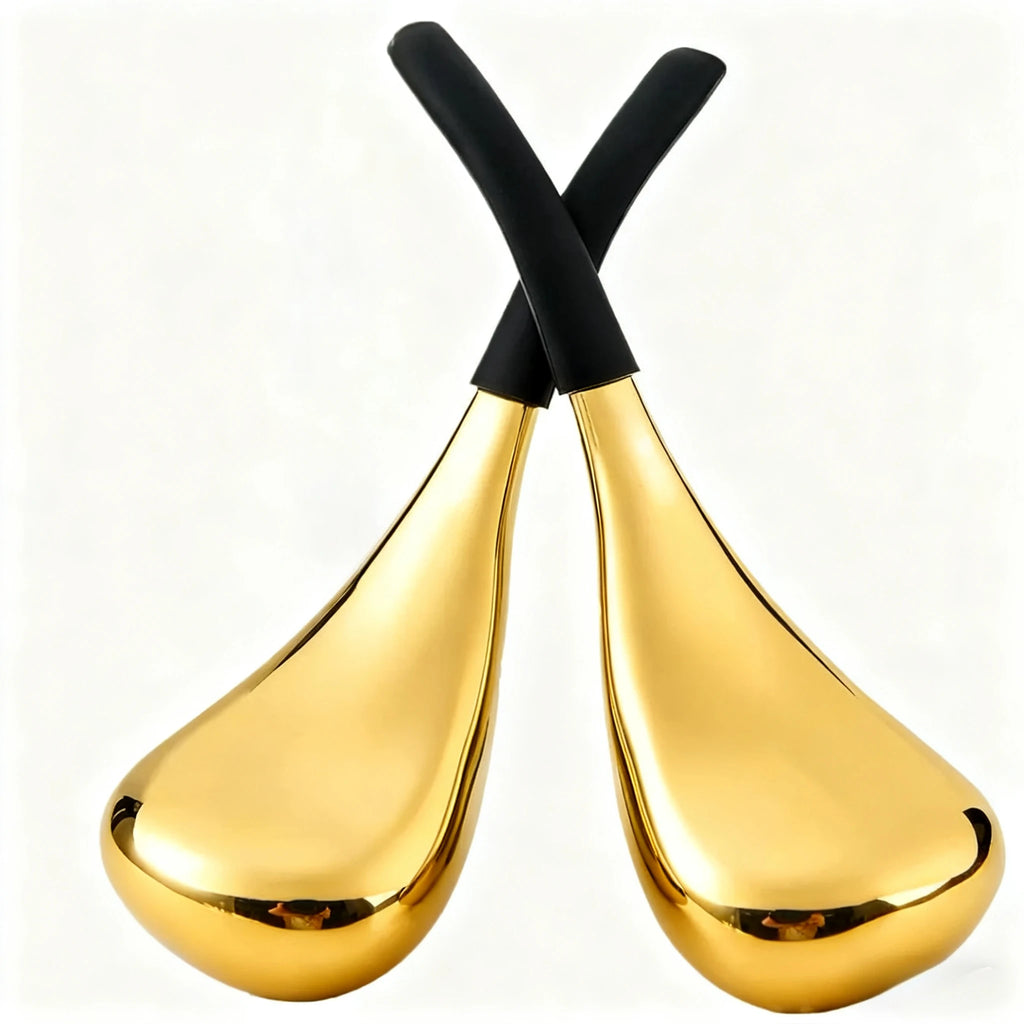 Two gold, teardrop-shaped facial cooling globes with black, ergonomic handles crossed against a white background.