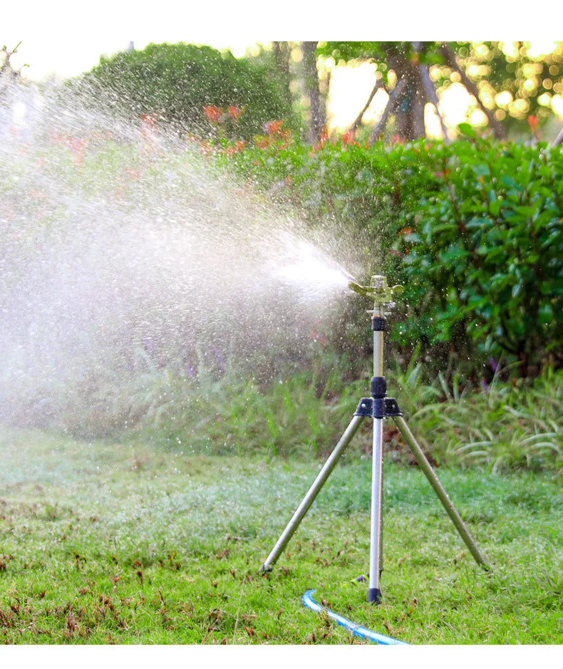 Tripod rotating lawn sprinkler with adjustable head, spraying water in a circular pattern