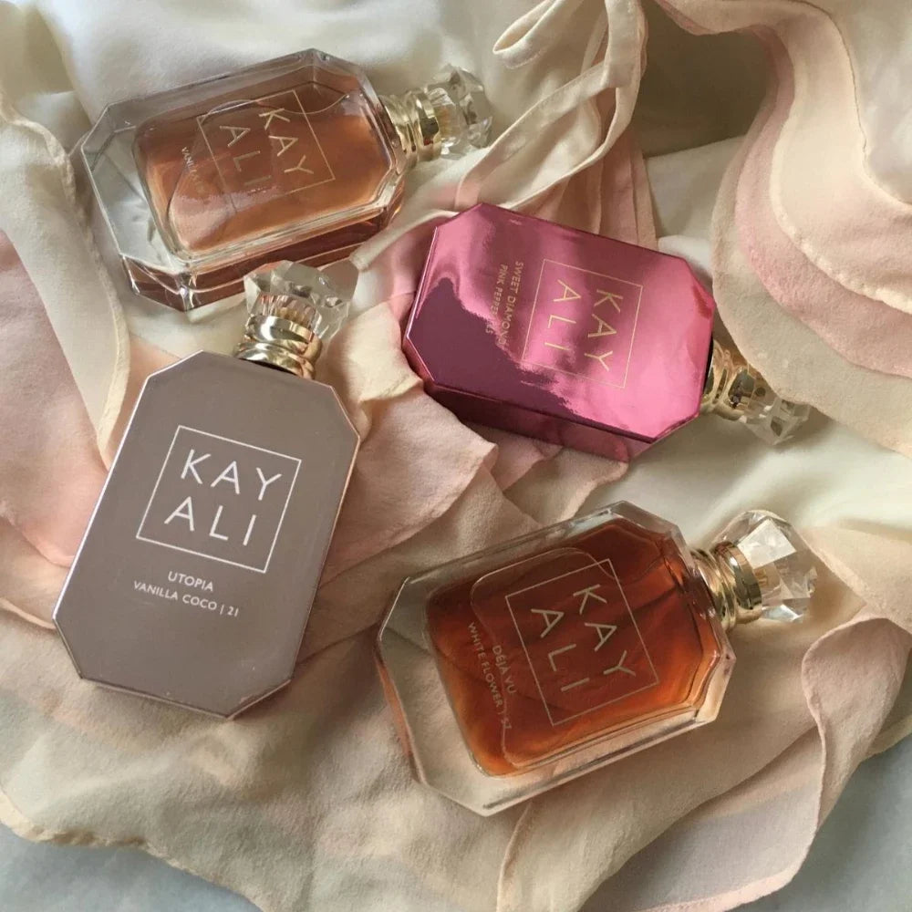 Kayali EDP perfume collection: luxury 100ml bottles with floral, vanilla, and woody scents on silk fabric.