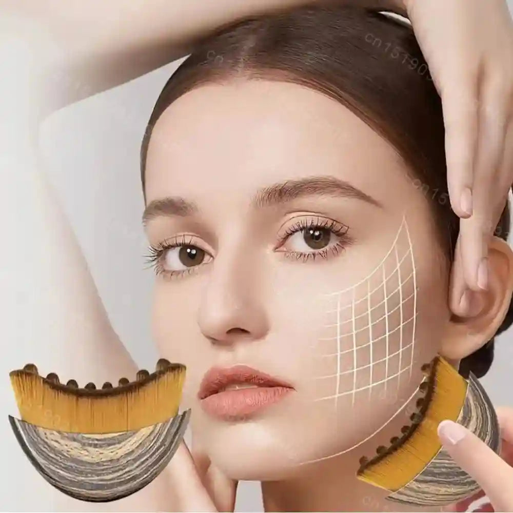 A person holding a curved, crescent-shaped facial massage brush with yellow bristles and a wood-grain textured handle.
