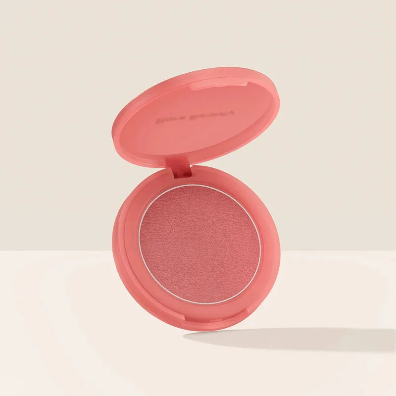 Rare Beauty soft-pink powder blush in a round, open compact case with a smooth, matte finish.