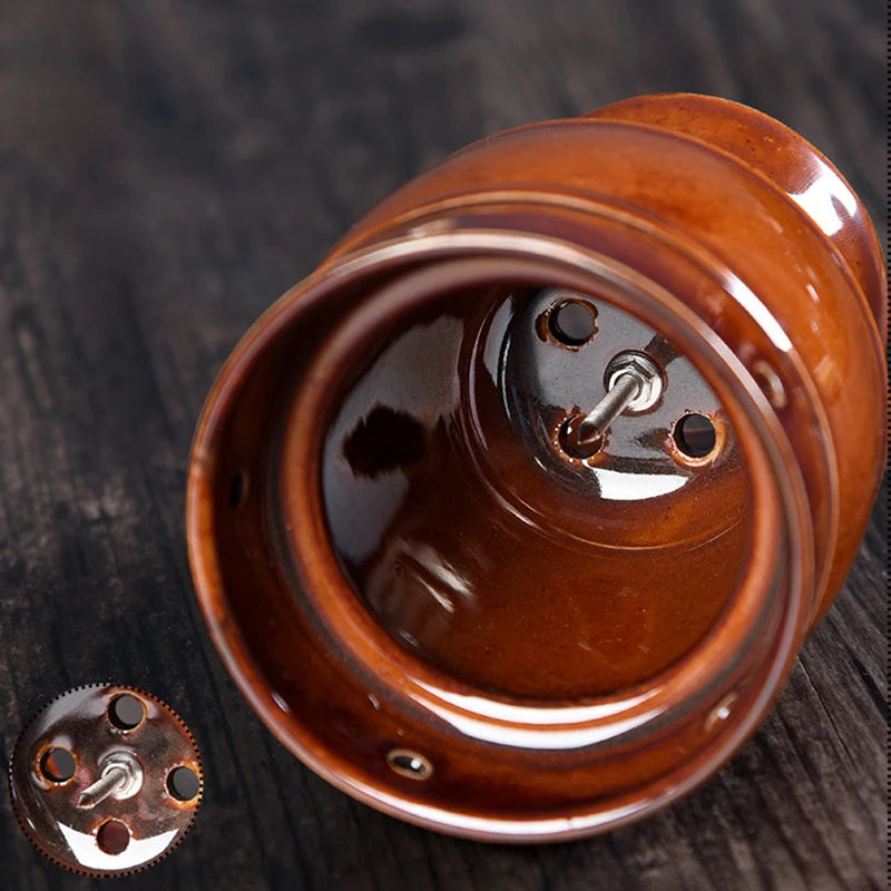 Glossy brown ceramic moxibustion cup with an interior metal spike and ventilation holes for thermal massage therapy.