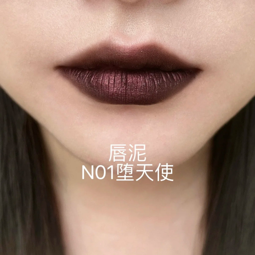 DE'LANCI dark blue gothic shimmer lip mud for a smoky look with high-pigment, fine-textured matte finish on lips.