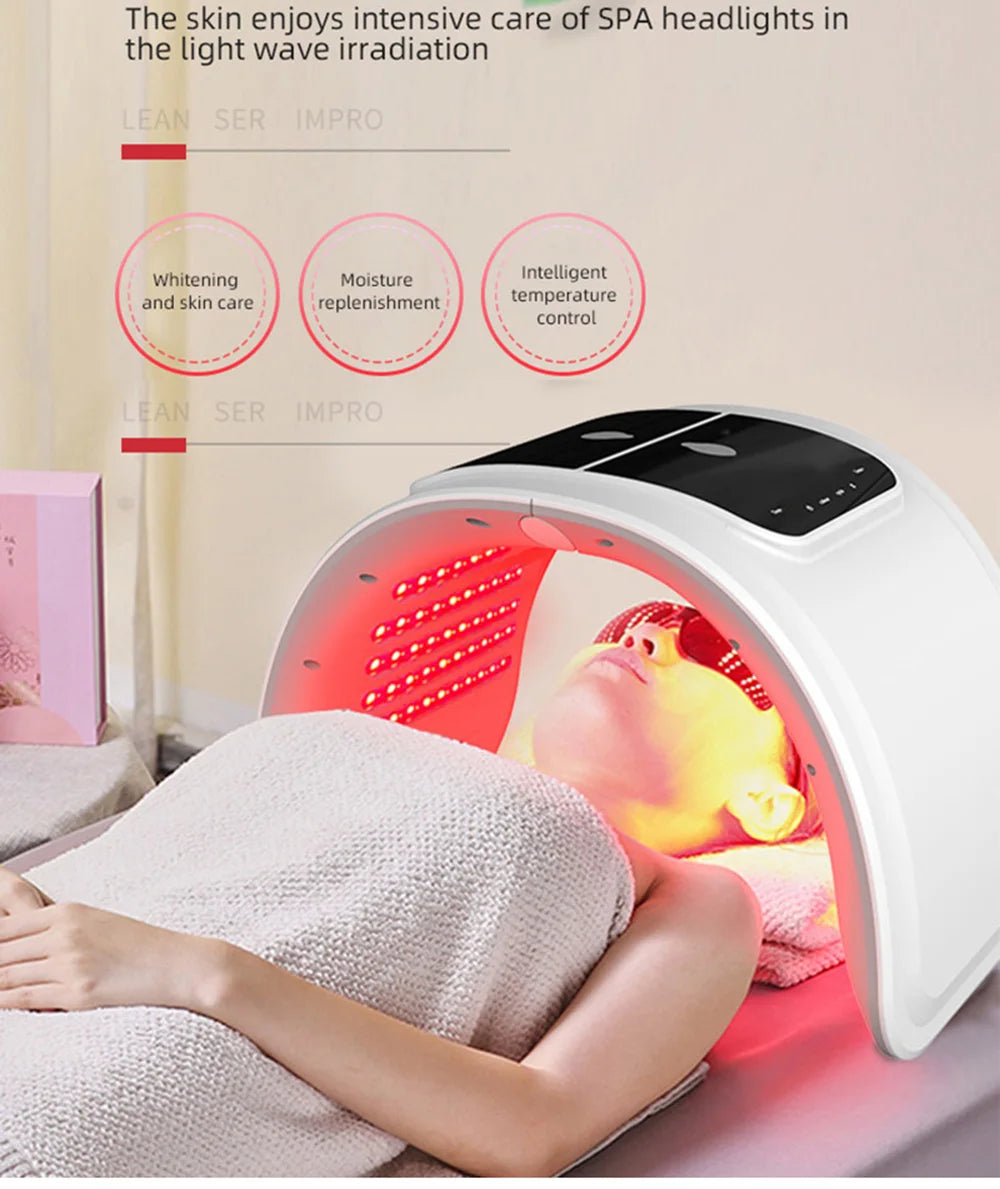 Person under a white arched LED light therapy mask emitting red light for facial skin rejuvenation.