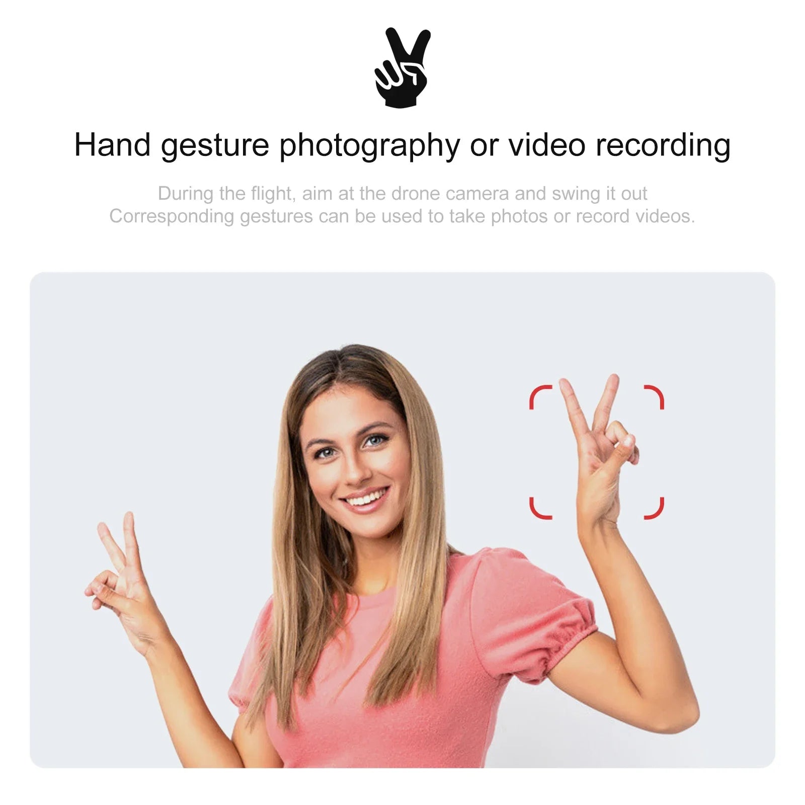 Woman wearing pink shirt makes a peace sign gesture to trigger drone camera capture, framed by red digital brackets.