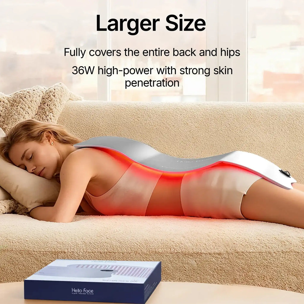 Woman lying on a couch with a large, flexible grey red-light therapy mat draped over her back emitting red light.