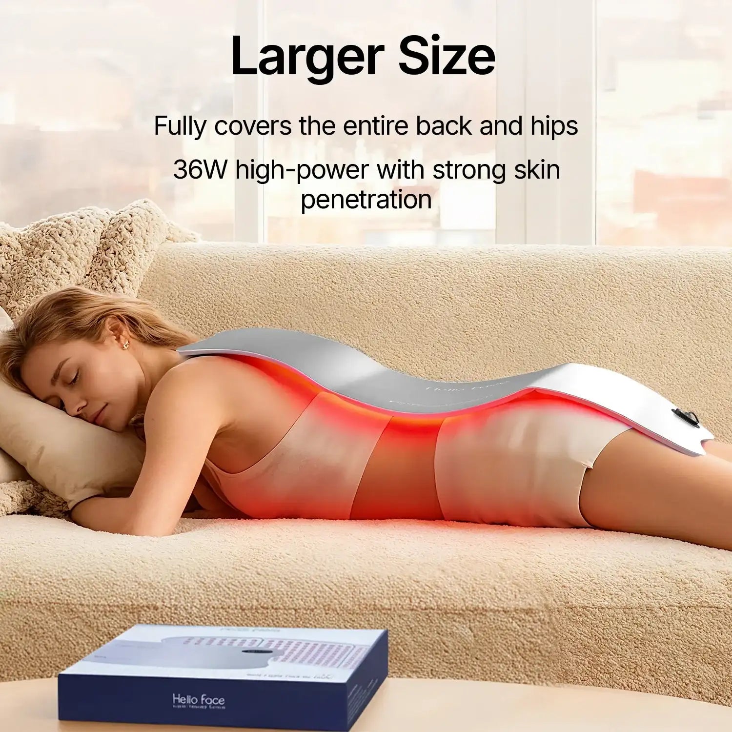 Woman lying on a couch with a large, flexible grey red-light therapy mat draped over her back emitting red light.