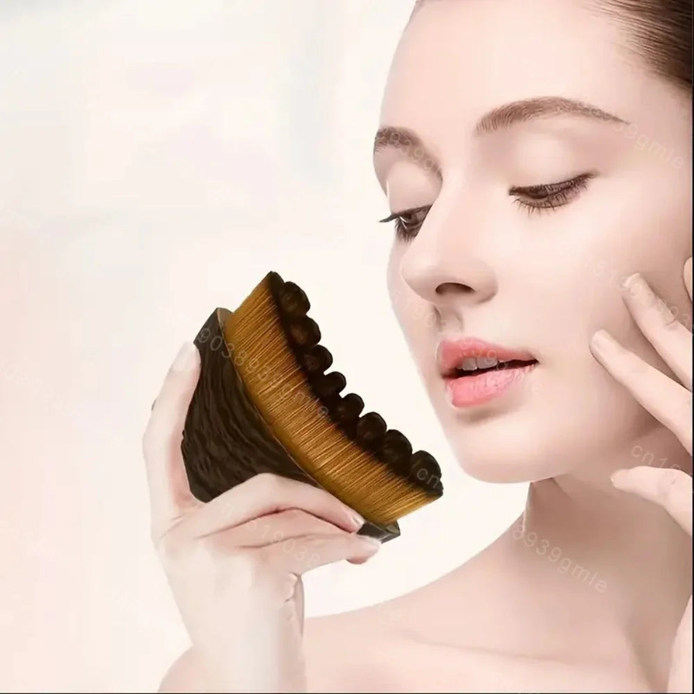 A woman holding a curved, black and gold ergonomic facial massage brush with dense, soft bristles.