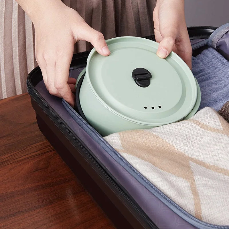Green electric cooking pot with lid being placed on the portable base