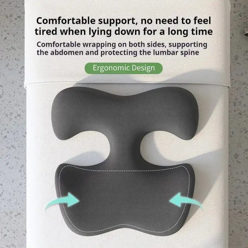 Dark gray ergonomic massage cushion for prone sleeping, featuring a contoured shape to support the abdomen and chest.