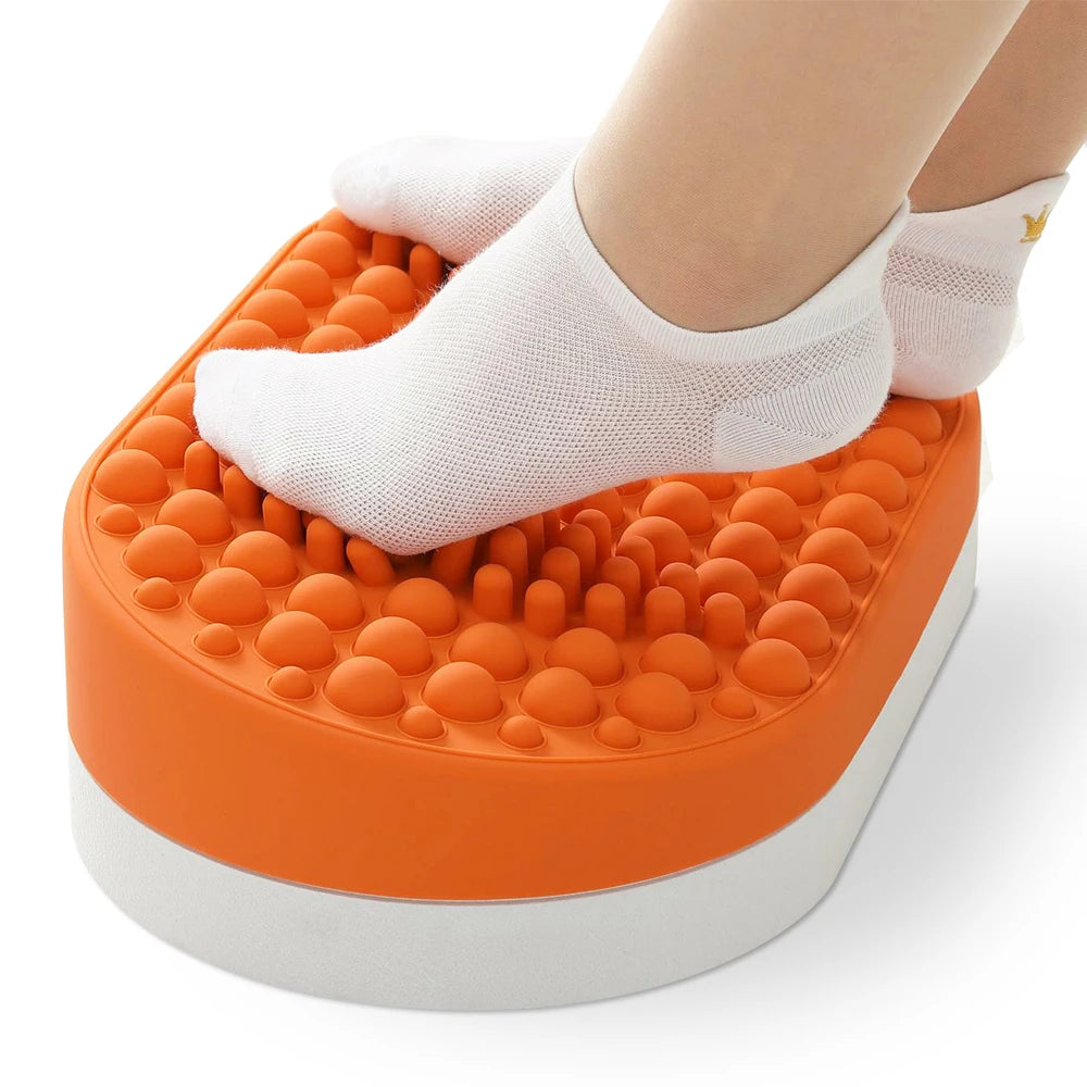 Orange silicone under-desk foot rest with textured massage nodules for home office plantar fasciitis relief.