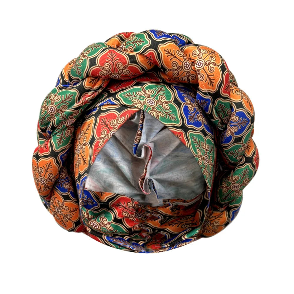 Tidesmit floral braided turban headwrap in vibrant red, orange, green, and blue on a black background, top-down view.