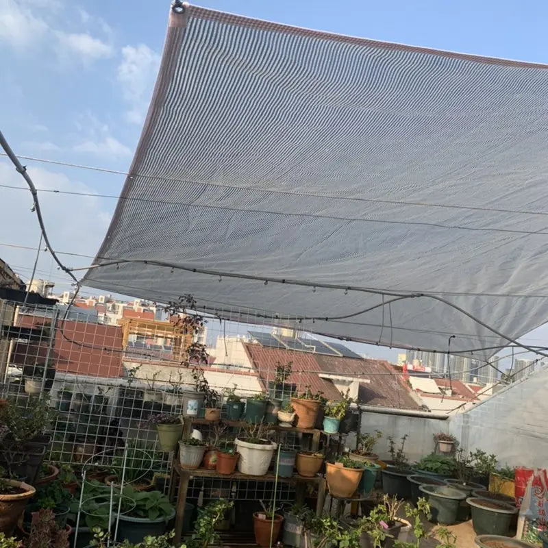 Aluminum foil sunshade net canopy covering a garden area with potted plants
