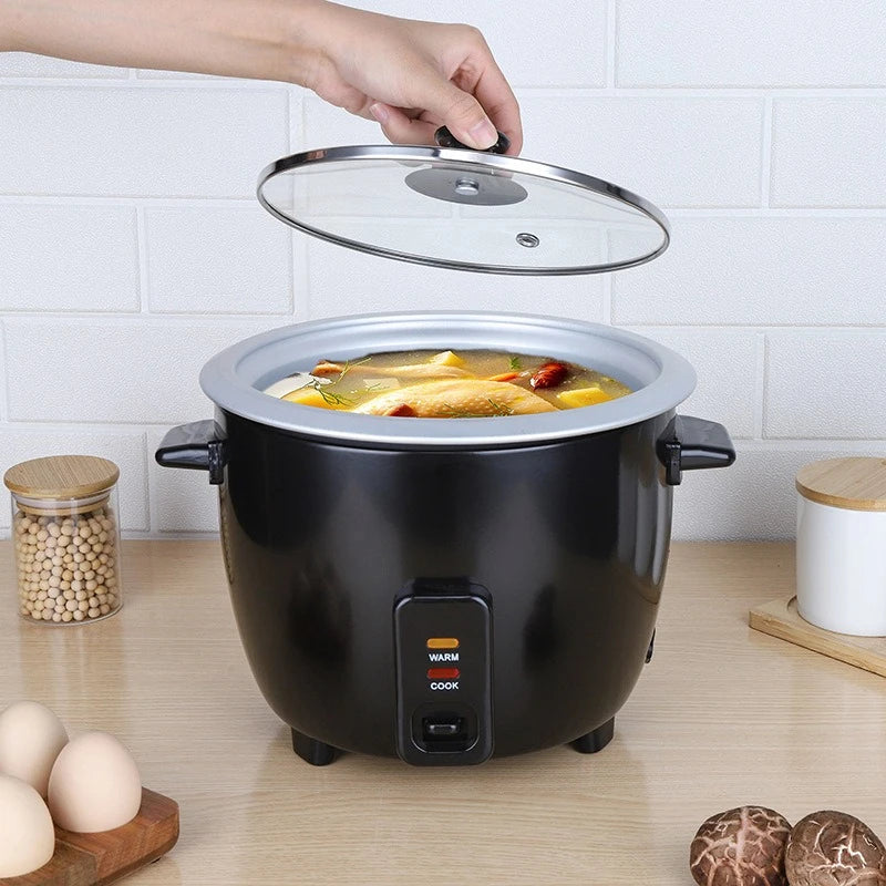 Mini electric rice cooker with glass lid and black inner pot, steaming meal inside