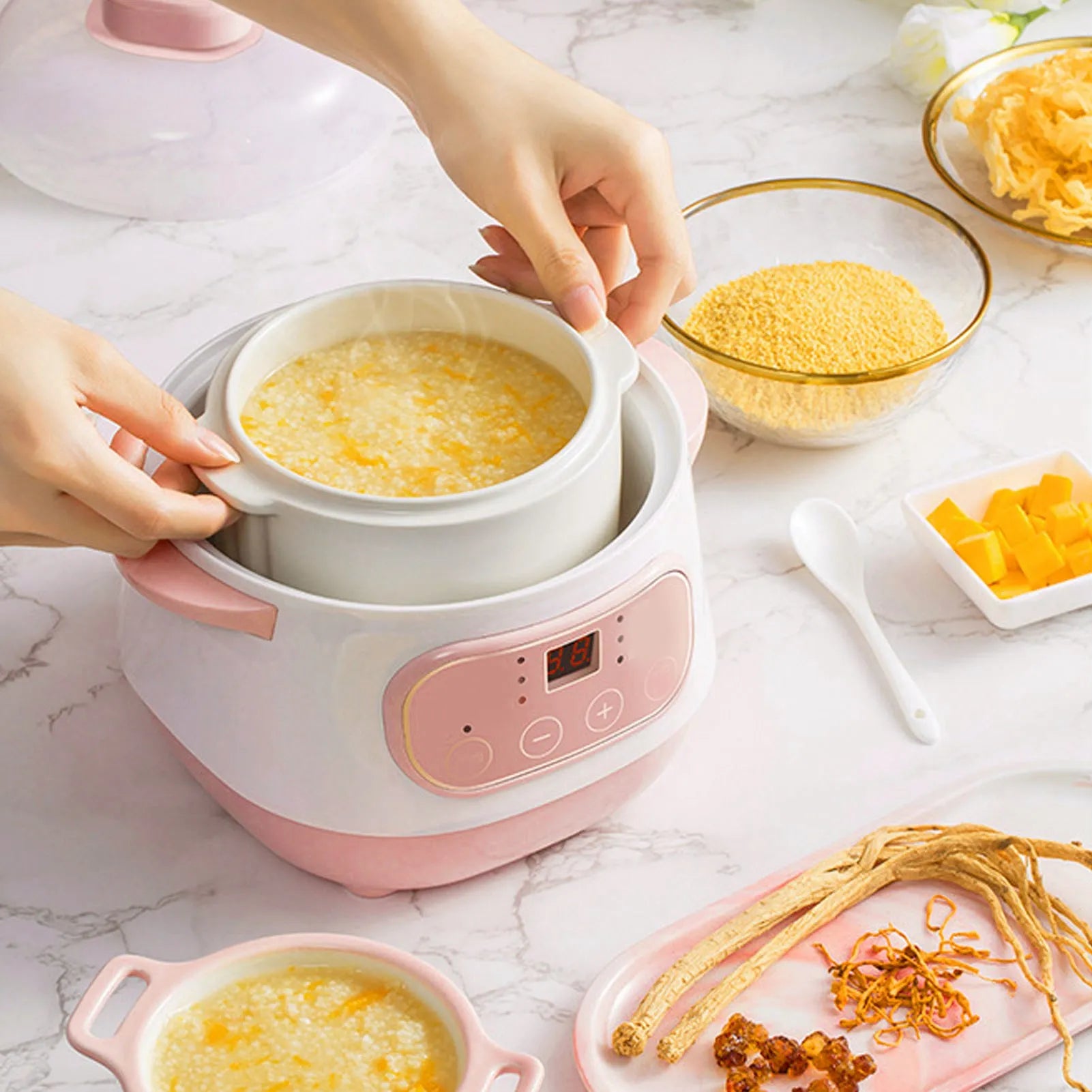 Pink mini electric rice cooker with ceramic inner pot, lid open with porridge cooking