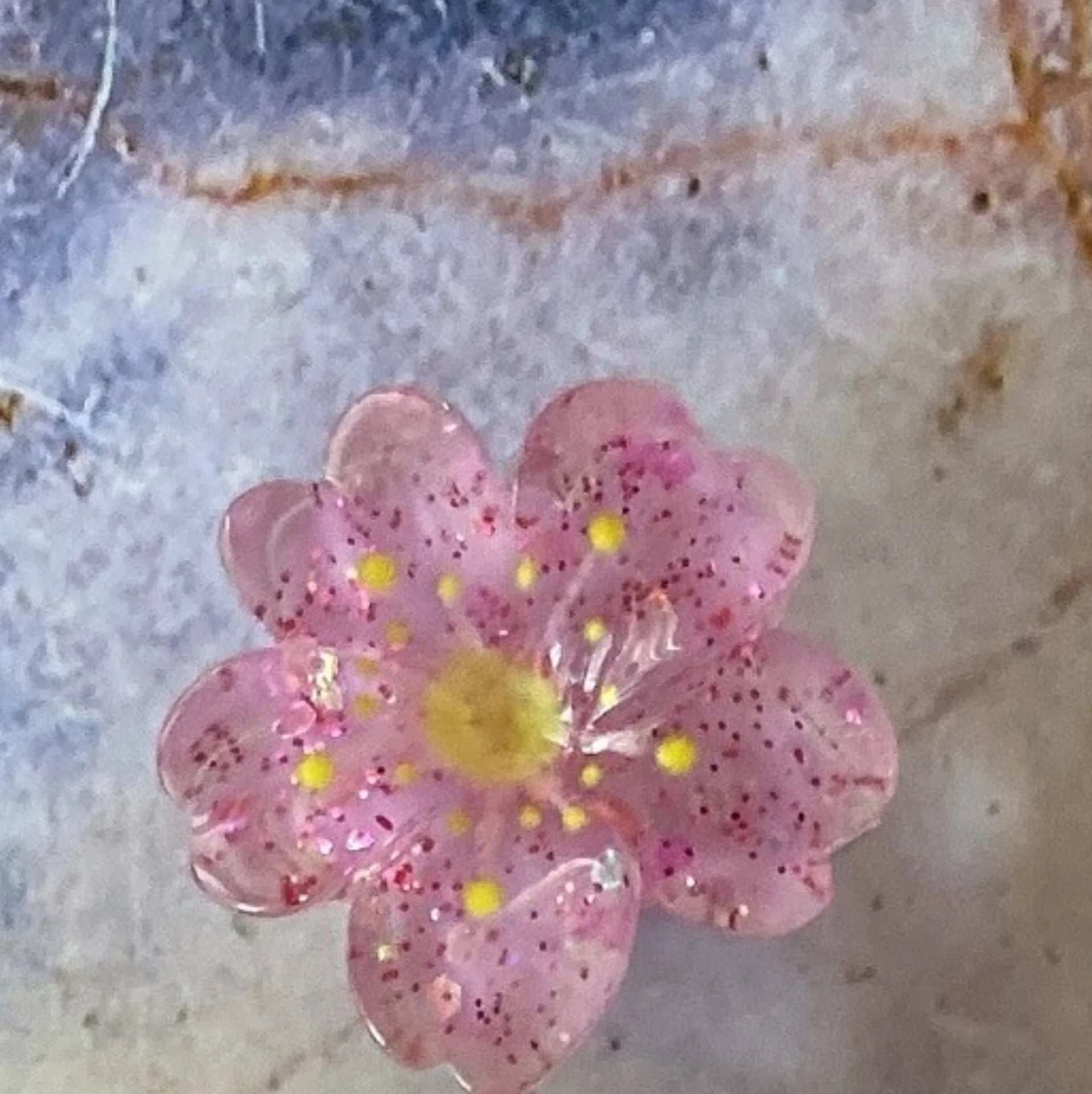 Pink glitter flower dust plug for Tamagotchi Uni. Silicone protective charm prevents port damage in style.