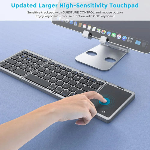 Grey foldable 3-section wireless keyboard with integrated touchpad, shown with a tablet on a stand.