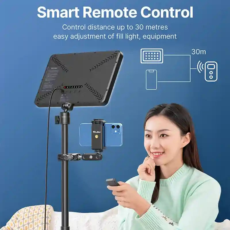 Black rectangular LED video light on a tripod stand with a phone holder, controlled wirelessly by a handheld remote.