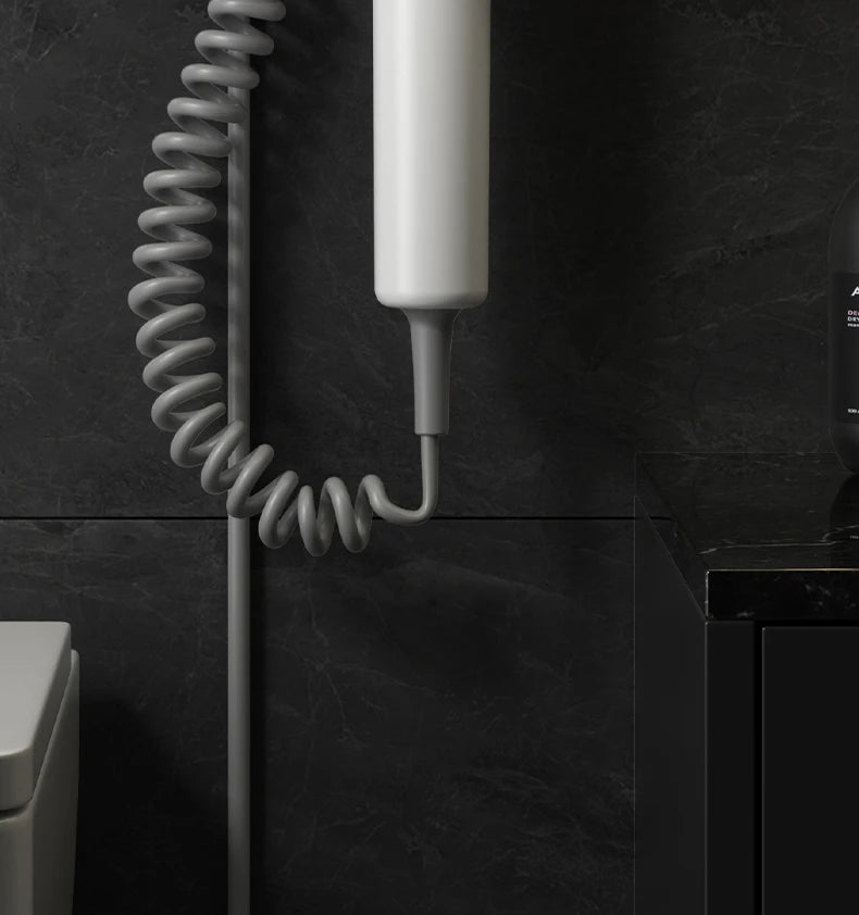 White wall-mounted 1300W hair dryer with coiled cord, perfect for modern hotel or home bathroom space-saving storage.
