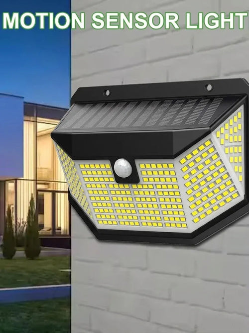 Black solar LED wall light mounted on a brick wall, featuring angled LED arrays and a central motion sensor.