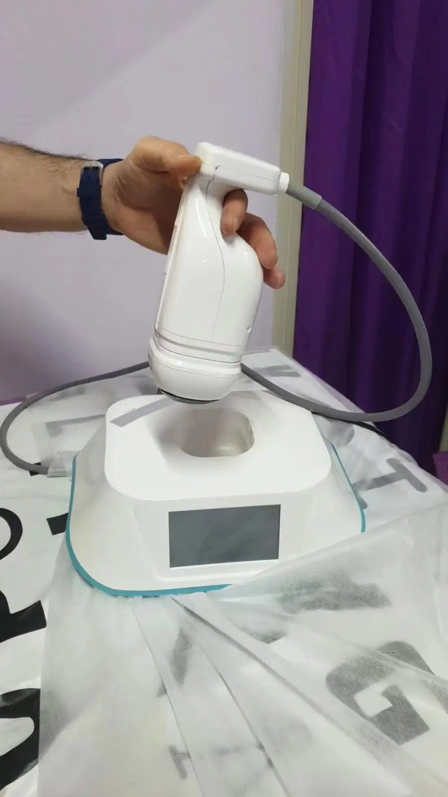 White handheld ultrasound beauty device with docking station for professional skin tightening and contouring.