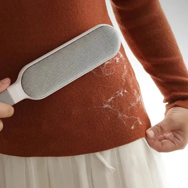 Double-sided reusable plush pet hair remover brush cleaning lint from an orange sweater, ideal for clothes and sofas.
