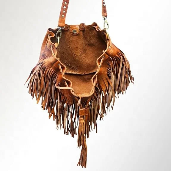 Tan leather bucket bag with bohemian fringe, drawstring closure, and adjustable shoulder strap for crossbody wear.