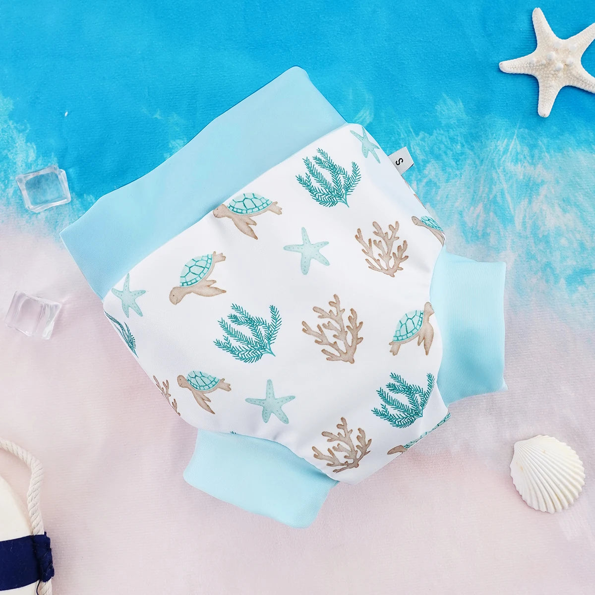 Small size baby swim diaper with ocean turtle, starfish, and coral print on a blue beach background.