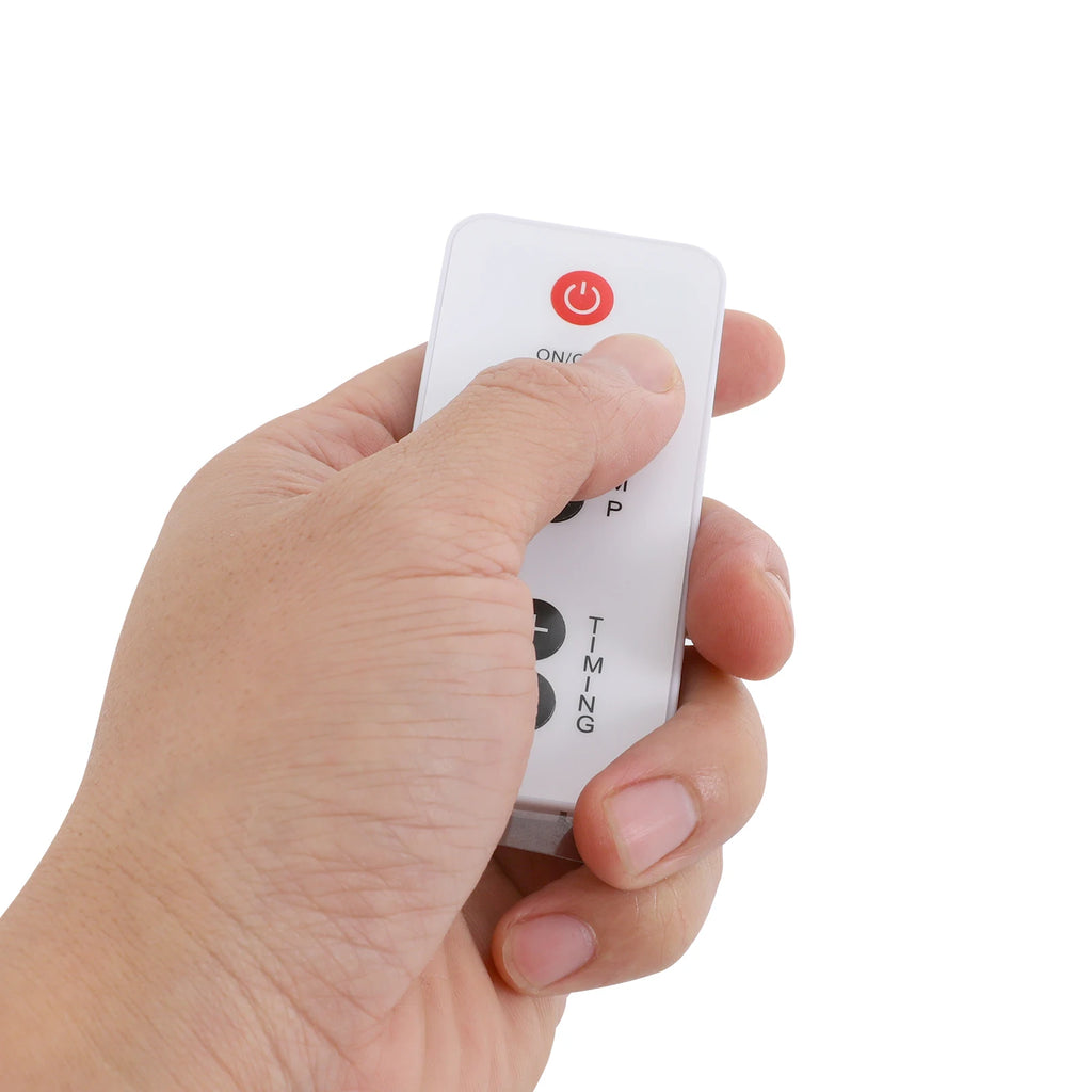 Hand holding white remote control for 275W heat lamp therapy device with power and timer adjustment buttons.