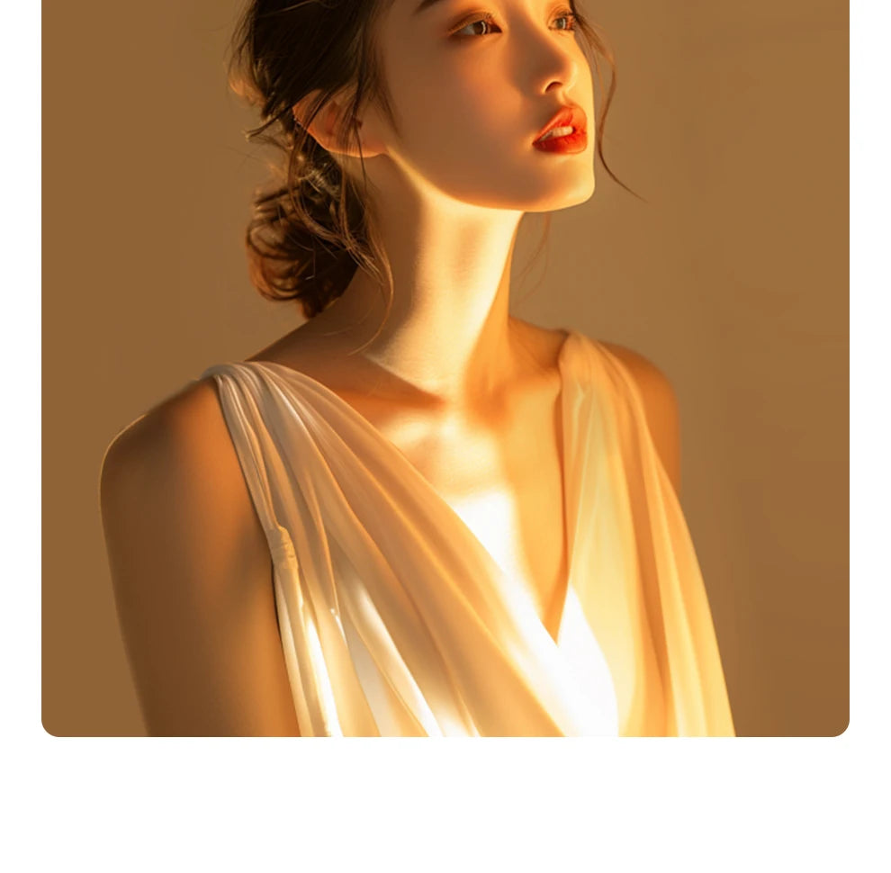 Woman wearing a sleeveless, cream-colored, draped V-neck dress made of lightweight fabric for elegant evening wear.