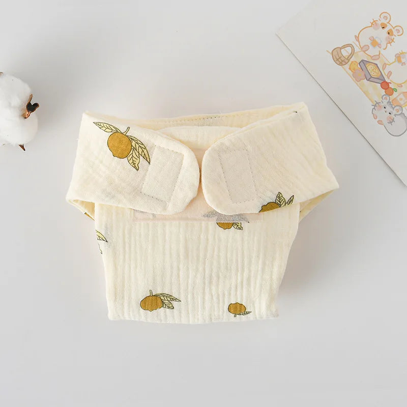 Cream-colored muslin baby cloth diaper with orange fruit pattern and velcro closure for baby care.