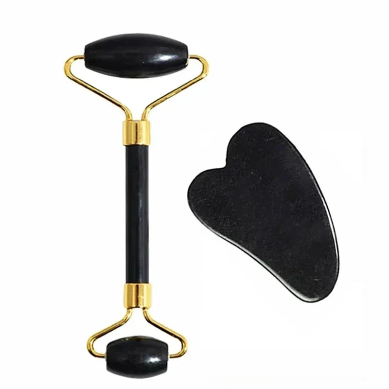 Black stone facial roller and heart-shaped gua sha tool with gold-tone hardware for skincare massage.