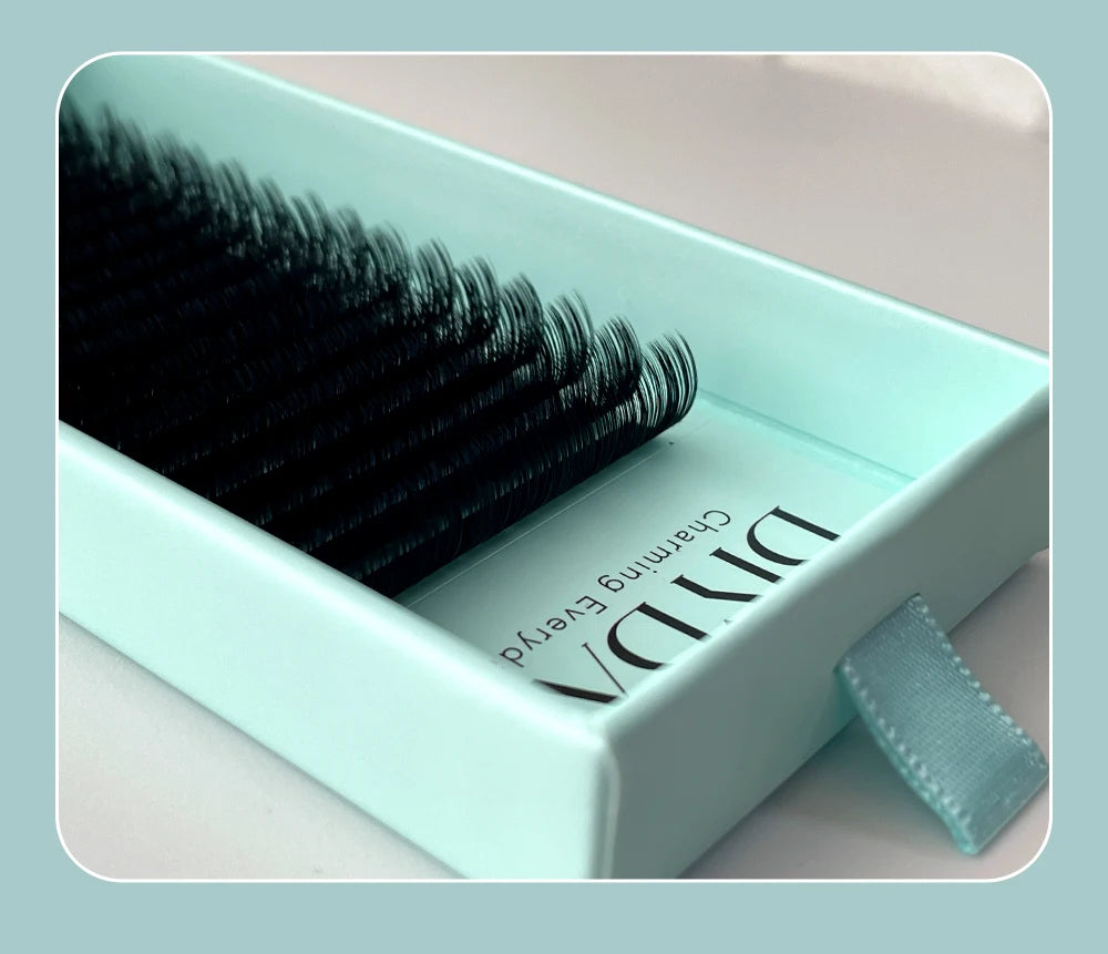 Tray of black mink individual eyelash extensions in a mint green box with a pull tab.