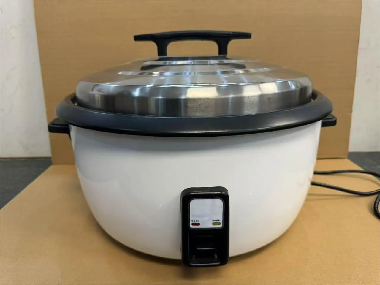Commercial rice cooker on countertop with black control base and stainless lid