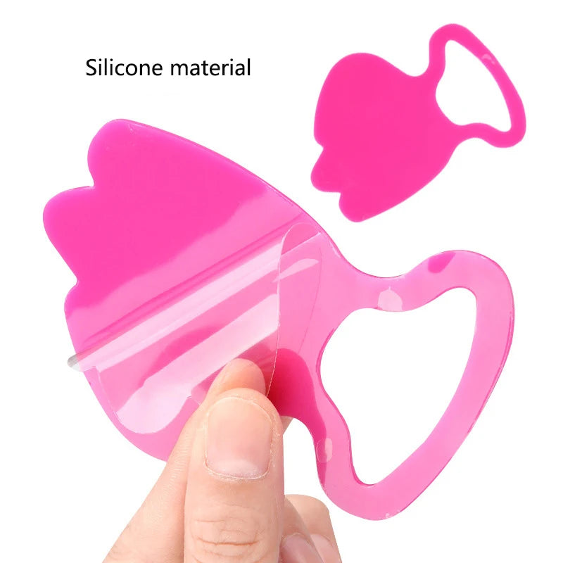 Two bright pink, reusable silicone anti-wrinkle patches with a heart-shaped design held by a hand.