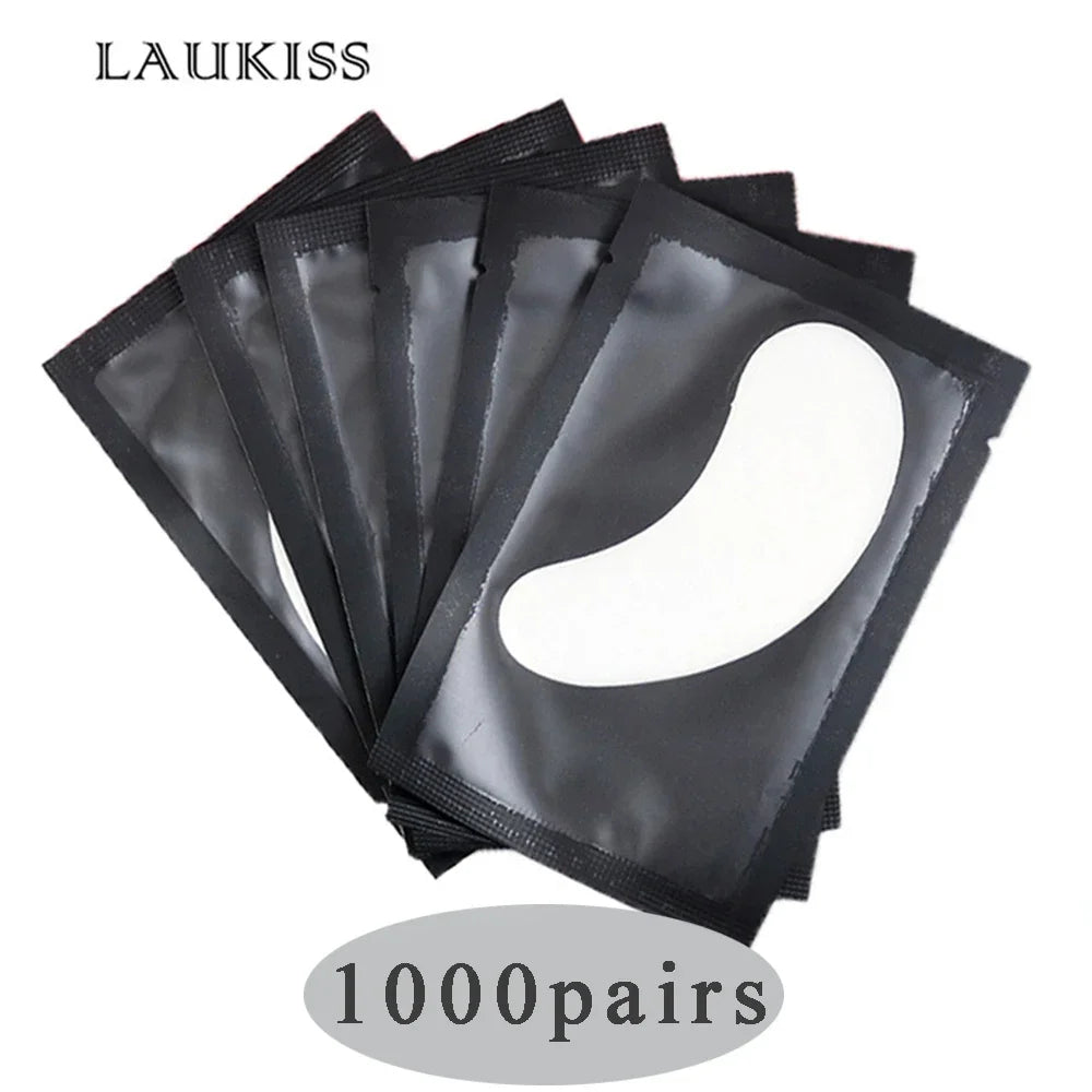 White gel under-eye patches in individual black foil sachets for eyelash extensions and professional beauty treatments.