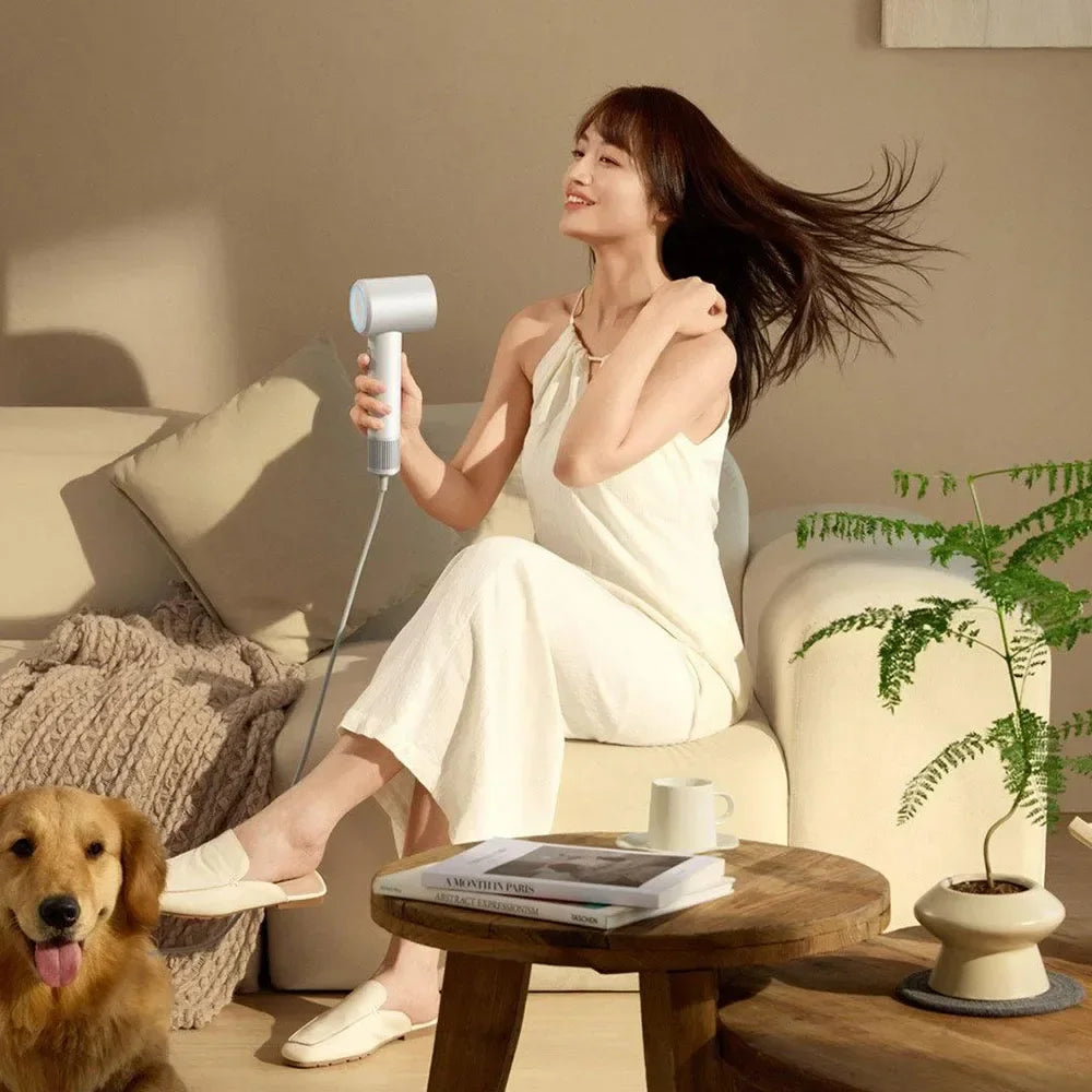 Woman using white MIJIA H501SE high-speed hair dryer with powerful negative ion technology for fast drying.