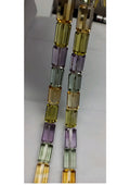 Close-up of multi-color faceted cylinder beads on a strand, yellow, lavender and mint