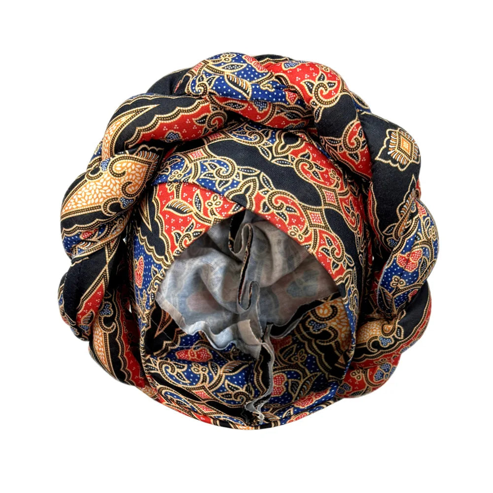 Tidesmit braided turban in black, red, and blue batik print with a wide crown and soft interior lining.