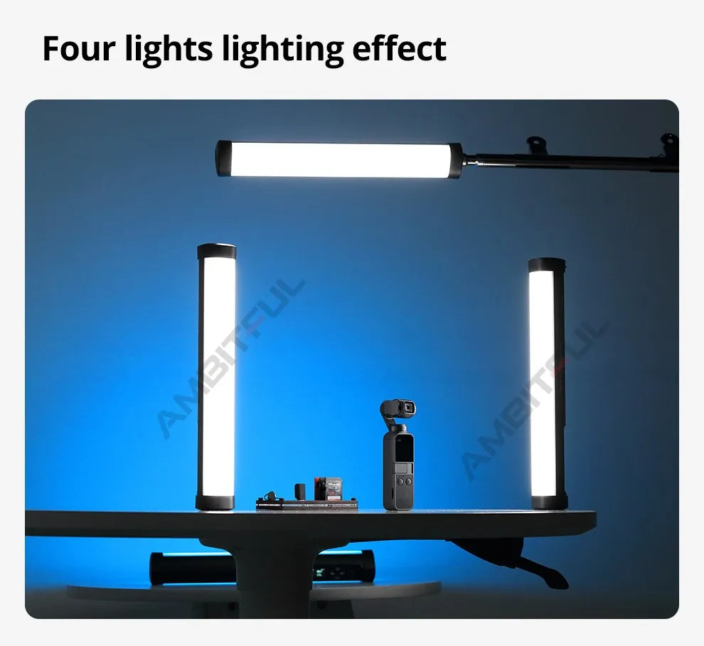 Four LED light tubes with black end caps illuminating a camera setup on a table for photography and video production.