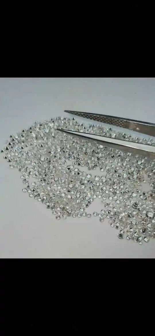 Loose lab-grown round brilliant diamond stones with metal tweezers, bright white sparkle