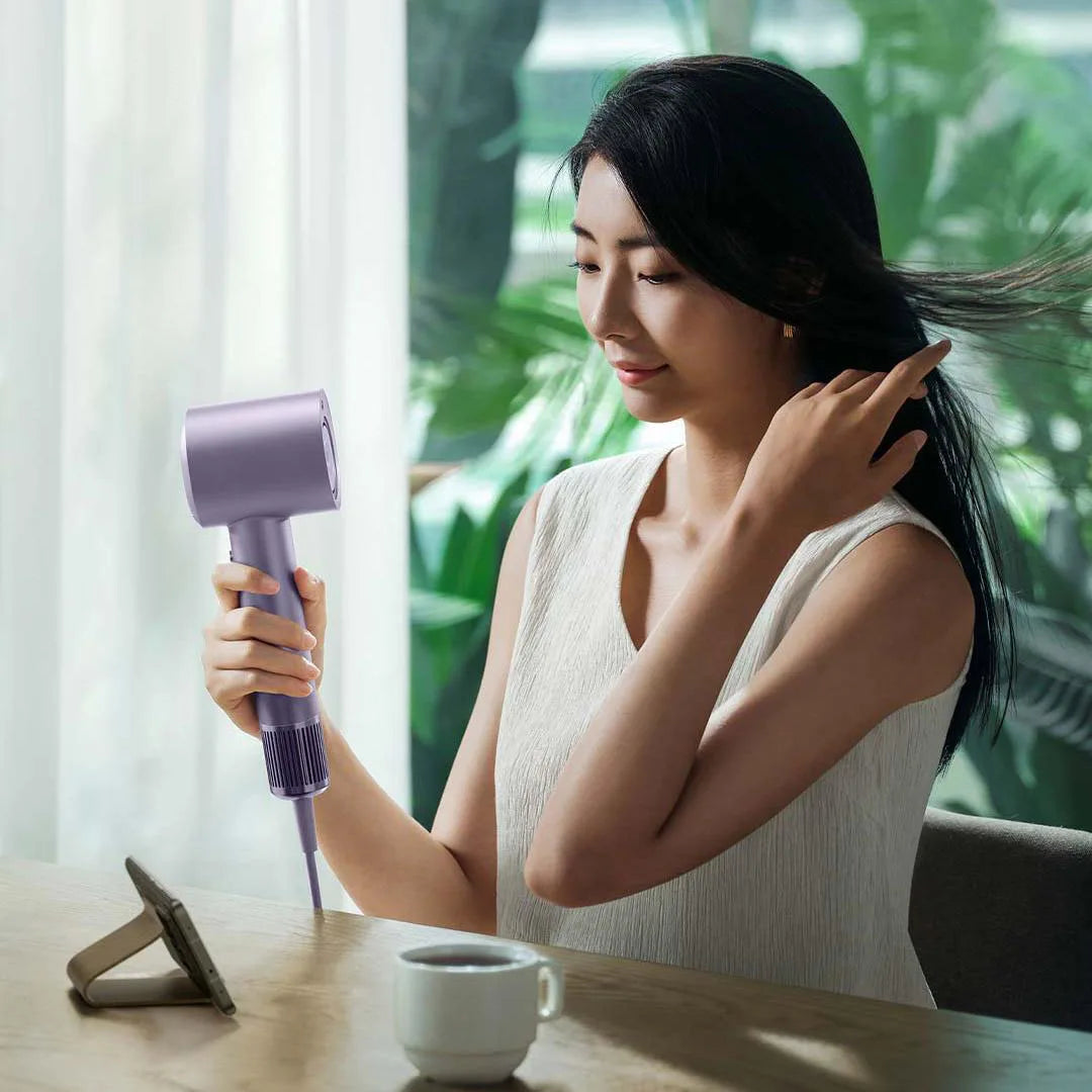 Woman using MIJIA H701 high-speed purple ion hair dryer for professional, quick-dry hair care at home.