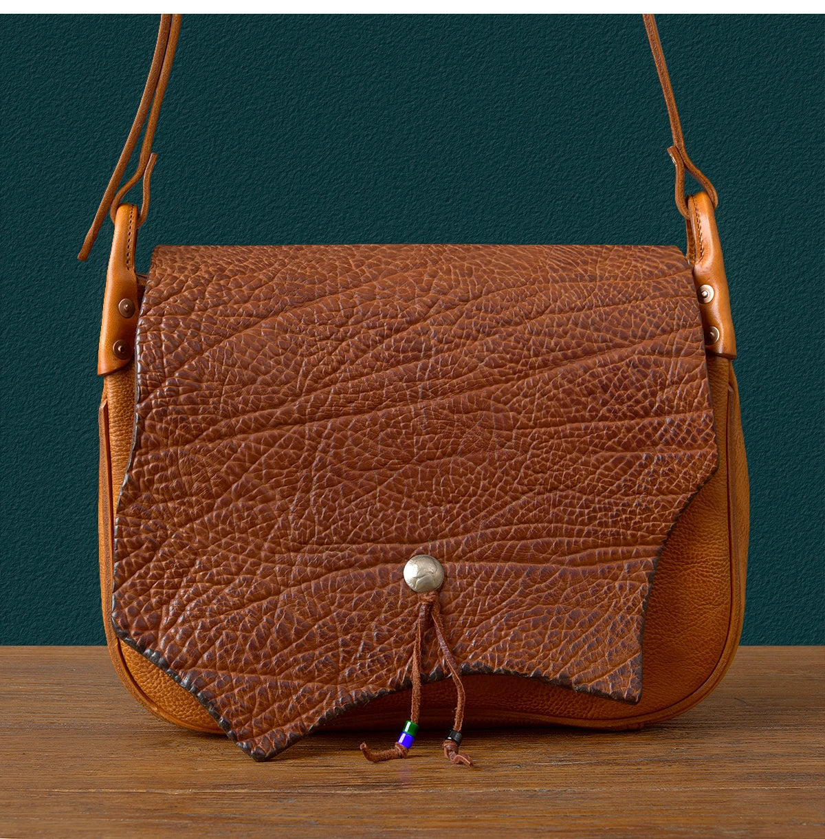 Vintage designer messenger bag in brown genuine cowhide leather with textured flap, snap closure, and shoulder strap.