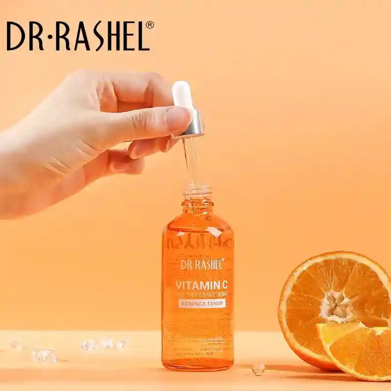 Vitamin C essence toner in an orange glass dropper bottle next to fresh orange slices.