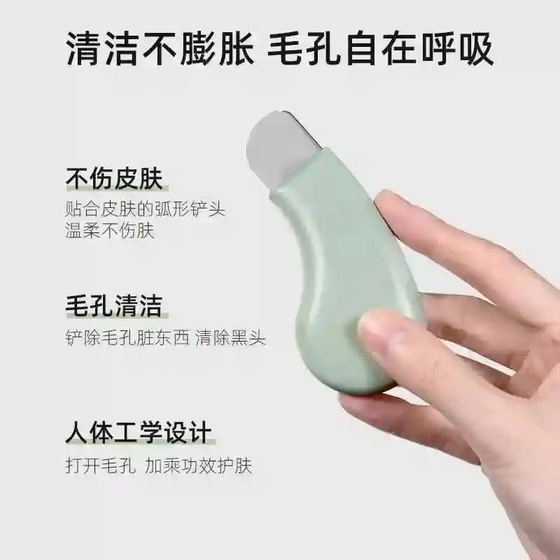 A hand holding a pale green, ergonomic pore cleansing tool with a flat metal spatula tip against text.