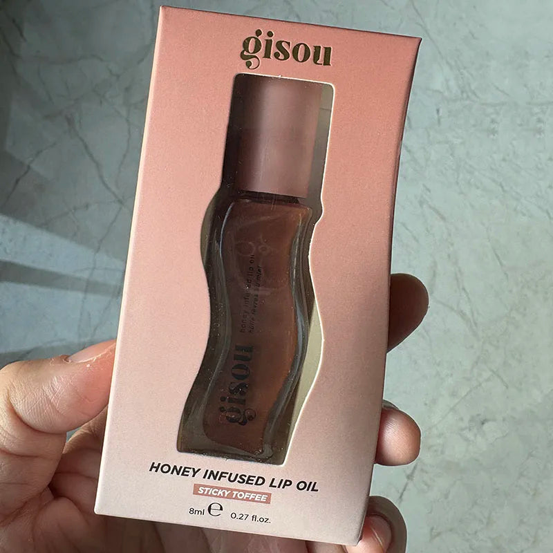 Gisou Honey Infused Lip Oil in Sticky Toffee, a brown moisturizing lip gloss in its original packaging.