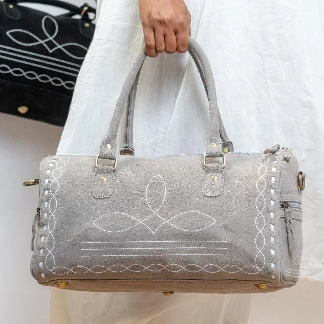 Grey suede weekend duffel trunk with elegant white decorative boot stitch detailing and durable metal hardware.