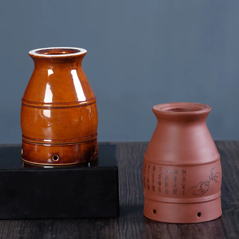 Two ceramic moxibustion therapy cups: one glossy amber, one matte terracotta with black calligraphy and graphics.